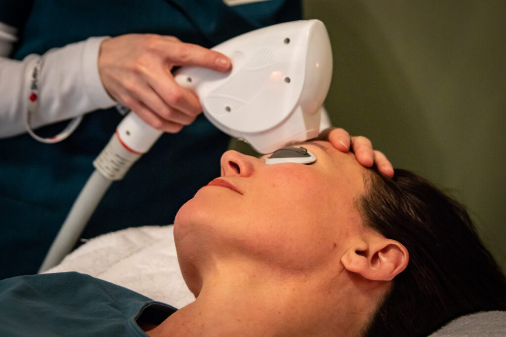 A woman getting her face cleaned by an esthetician.