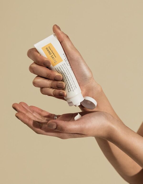 A person holding onto a tube of lotion