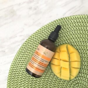 A bottle of vitamin e oil next to a cut up mango.