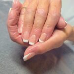 A woman is holding her hands with french manicure.