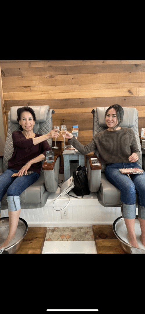 Two women sitting in chairs holding wine glasses.